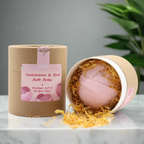 Bombe de bain rose de luxe tenue dans la main, effervescence dans l'eau, enrichie en Beurre de Karité, Absolue de Rose et Encens pour la détente et l'hydratation de la peau.